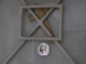 In this Jan. 5, 2018 photo, Luz Maria Alvarez Lopez, 50, is reflected in the small mirror which adorns her apartment's front door along with a simple reed cross, in the earthquake damaged building at Independencia 18 in Mexico City. Alvarez has lived in the building for 29 years and her family was occupying four of its 37 apartments.