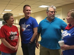In this Feb. 23, 2018, photo, West Virginia teachers, from left, Christi Phillips, Cody Thompson, Sam Brunett and Kristie Skidmore discuss a teachers strike at the state Capitol in Charleston, W.Va. Phillips said she also was involved in a teachers strike in 1990. She said the difference in the two was the speed at which this year's walkout happened due to the use of social media.