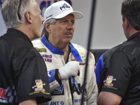 John Force talks to crew members after his Funny Car blew an engine and destroyed the body of his dragster, Friday, March 16, 2018, at the NHRA Gatornationals in Gainesville, Fla. Force sustained a cut on the back of his right hand. He had it bandaged at the end of the track, but did not need stitches.