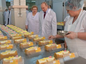 Russian President Vladimir Putin, centre, looks at bread and confectionery during his visit to the Samara bakery and confectionery factory on the eve of International Women's Day in Samara, Russia, Wednesday, March 7, 2018.
