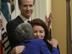 State Sen. Toni Atkins, D-San Diego, center is is hugged by Sen. Hannah-Beth Jackson, D-Santa Barbara, after she was sworn in as the new Senate president pro tempore Wednesday, March 21, 2018, in Sacramento, Calif. In the background Lt. Gov. Gavin Newsom applauds Atkins who becomes the first woman to lead the California Senate.