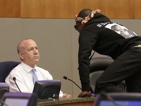 Stevante Clark jumps on the dais and shouts at Sacramento Mayor Darrell Steinberg, left, during a city council meeting, Tuesday, March 27, 2018, in Sacramento, Calif. Clark, the brother of Stephon Clark, who was shot and killed by Sacramento Police officers a week earlier, disrupted the meeting and demanded to speak. The city council adjourned for a roughly 15-minute recess as a result of the disruption.