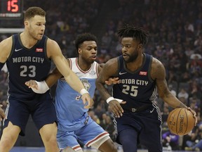 Sacramento Kings guard Buddy Hield, center, tries to fight through the screen set by Detroit Pistons forward Blake Griffin, left, as he guards Pistons forward Reggie Bullock, right during the first half of an NBA basketball game Monday, March 19, 2018, in Sacramento, Calif.