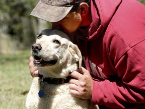 In this Thursday, March 22, 2018 photo, Beaufort resident, Mason Ringer kisses the head of Woody, the dog that rescued him from the Okatie River, in Okatie, S.C. The dog jumped into the choppy, 58-degree (14 C) water on Wednesday and pulled Ringer, who was struggling after his boat had capsized, toward a nearby dock.