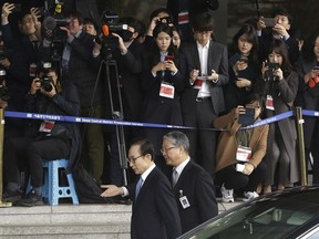 Former South Korean President Lee Myung-bak, center left, is escorted upon arrival for questioning over bribery allegations at Seoul Central District Prosecutors' Office in Seoul, South Korea, Wednesday, March 14, 2018.