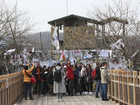 Visitors take pictures in front of banners placed on a barbed wire fence with messages wishing for the reunification of the two Koreas at the Imjingak Pavilion in Paju, near the border with North Korea, South Korea, Wednesday, March 7, 2018. The meeting between North Korean leader Kim Jong Un and South Korean envoys marked the first time South Korean officials have met with the young North Korean leader in person since he took power after his dictator father's death in late 2011. It's the latest sign that the Koreas are trying to mend ties after one of the tensest years in a region that seems to be permanently on edge.