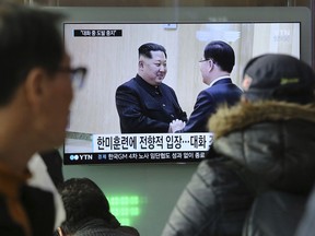 People watch a TV screen showing North Korean leader Kim Jong Un, left, meeting with South Korean National Security Director Chung Eui-yong in Pyongyang, North Korea, at the Seoul Railway Station in Seoul, South Korea, Wednesday, March 7, 2018. After years of refusal, North Korean leader Kim Jong Un is willing to discuss the fate of his atomic arsenal with the United States and has expressed a readiness to suspend nuclear and missile tests during such talks, a senior South Korean official said Tuesday. Korean characters seen on the screen read: "South Korea-U.S. joint military drills."