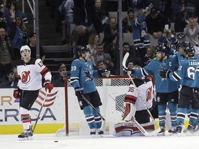 San Jose Sharks' Joe Pavelski, third from right, is hugged by teammates after scoring against the New Jersey Devils during the first period of an NHL hockey game Tuesday, March 20, 2018, in San Jose, Calif.