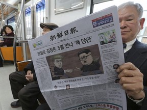 A passenger reads a newspaper with the headline outlining a planned summit meeting between North Korean leader Kim Jong Un and U.S. President Donald Trump, left, at subway train in Seoul, South Korea, Saturday, March 10, 2018.