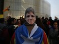 A pro-independence demonstrator wears a Carles Puigdemont mask during a protest of the detention of the deposed leader of Catalonia's pro-independence party in Barcelona, Spain, Sunday, March 25, 2018.