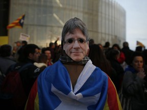 A pro-independence demonstrator wears a Carles Puigdemont mask during a protest of the detention of the deposed leader of Catalonia's pro-independence party in Barcelona, Spain, Sunday, March 25, 2018.