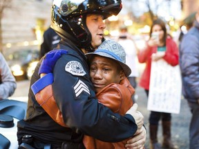 In this Nov. 25, 2014, file photo provided by Johnny Nguyen, Portland police Sgt. Bret Barnum, left, and Devonte Hart, 12, hug at a rally in Portland, Ore., where people had gathered in support of the protests in Ferguson, Mo. Authorities have said two women and three children were killed Monday, March 26, 2018, when their SUV fell from a cliff along Pacific Coast Highway in Mendocino County. Hart is one of the three other children still missing.