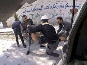 This photo released Tuesday, March 13, 2018, by the Syrian civil defence group known as the White Helmets, shows members of the White Helmets carrying a man who was wounded during airstrikes and shelling by Syrian government forces, in Ghouta, a suburb of Damascus, Syria.