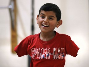 FILE - In this Dec. 10, 2016 file photo, Syrian refugee Ahmad Alkhalaf, whose arms were blown off above the elbows in a refugee camp bomb blast in 2014, smiles while playing with friends during a day camp in Sharon, Mass. In 2018, after seven years of war in Syria, the United Nations has one thing to say: Stop the war on children. Of Syria's estimated 10 million children, 8.6 million are now in dire need of assistance and nearly 6 million children are displaced or living as refugees.