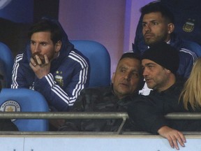 Argentina's Lionel Messi, left, and Sergio Aguero, top right, sit on the bench before the international friendly soccer match between Argentina and Italy at the Etihad Stadium in Manchester, England, Friday, March 23, 2018.