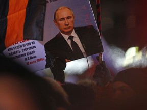 A person holds a banner of Russian President Vladimir Putin in Manezhnaya square, near Kremlin in Moscow, Sunday, March 18, 2018. An exit poll suggests that Vladimir Putin has handily won a fourth term as Russia's president, adding six more years in the Kremlin for the man who has led the world's largest country for all of the 21st century.