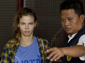 In this Feb. 28, 2018 photo, a police officer escorts Anastasia Vashukevich from a detention centre in Pattaya, south of Bangkok, Thailand, after she was arrested in the Thai resort city of Pattaya while giving sex lessons to Russian tourists.