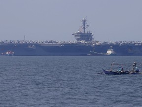 In this Feb. 17, 2018, file photo, fishermen on board a small boat pass by the USS Carl Vinson aircraft carrier at anchor off Manila, Philippines, for a five-day port call.