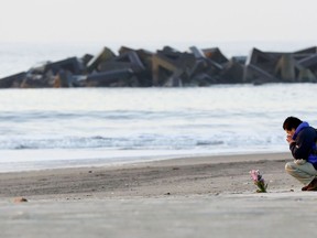 A man prays after offering flowers in Arahama coastal area where the tsunami struck in 2011, in Sendai city, northern Japan, Sunday, March 11, 2018.  Japan marks the seventh anniversary of the strong quake and Tsunami which ravaged the coastal area of Northern Japan and triggered the nuclear accident at Fukushima Dai-ichi nuclear plant.