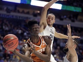 Texas forward Mohamed Bamba passes under pressure from Nevada guard Kendall Stephens (21) and forward Caleb Martin, right, in the first half of a first-round game of the NCAA college basketball tournament in Nashville, Tenn., Friday, March 16, 2018.