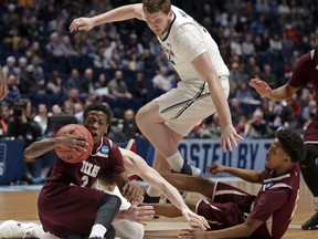 Texas Southern guard Demontrae Jefferson (3) corrals the ball as teammate guard Derrick Bruce falls to the court as Xavier forward Sean O'Mara (54) climbs over, in the first half of a first-round game of the NCAA college basketball tournament in Nashville, Tenn., Friday, March 16, 2018.