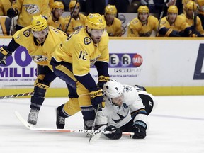 San Jose Sharks center Joe Pavelski (8) falls as he chases the puck with Nashville Predators center Mike Fisher (12) and right wing Ryan Hartman (38) in the first period of an NHL hockey game Thursday, March 29, 2018, in Nashville, Tenn.