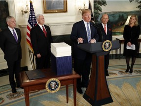 U.S. President Donald Trump speaks to the press about the $1.3 trillion spending bill passed by Congress early Friday, with Vice President Mike Pence (2nd-L), Defense Secretary Jim Mattis, (L), and Commerce Secretary Wilbur Ross (R) in the Diplomatic Room of the White House on March 23, 2018 in Washington, DC. After threatening to veto the legislation earlier today, President Trump announced he had signed the bill, avoiding a government shutdown.