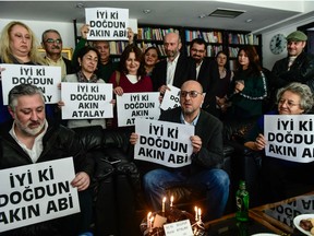 Freed journalists, editor-in-chief of Cumhuriyet Turkish daily newspaper, Murat Sabuncu (L), and Turkish journalist Ahmet Sik (C), surrounded by fellow colleagues, hold placards reading "Happy Birthday" for the paper's chairman, Akin Atalay who stayed in jail, on March 10, 2018 in Istanbul.  Two Turkish journalists walked free from prison on March 9 after over a year behind bars in the trial on terror-related charges of staff from the opposition Cumhuriyet newspaper, seen as a test of press freedom under President Recep Tayyip Erdogan.