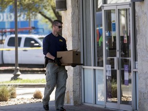 An FBI official carries items into a FedEX Office store Tuesday, March 20, 2018, in the southwest Austin suburb of Sunset Valley, Texas, as authorities investigate a recent string of package bombs.