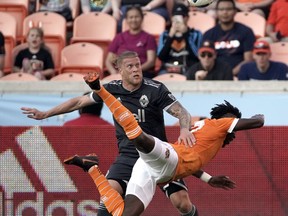 Houston Dynamo's Alberth Elis, right, dives for the ball in front of Vancouver Whitecaps's Marcel de Jong during the first half of an MLS soccer game Saturday, March 10, 2018, in Houston.
