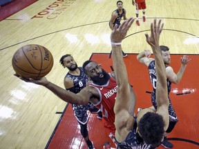 Houston Rockets' James Harden, center, shoots as San Antonio Spurs' Derrick White, bottom, defends during the second half of an NBA basketball game Monday, March 12, 2018, in Houston.