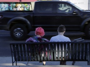 A couple wait at a bus stop, Tuesday, March 20, 2018, in Austin, Texas, a city that has seen five bombings that have killed two people and badly wounded four others since March 2. The recent blasts have sent a deep chill through a hipster city known for warm weather, live music, barbeque and, above all, not taking itself too seriously.