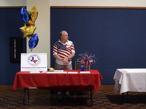 In this Tuesday, Feb. 13, 2018, photo, Kerry Ledford mans a booth at a Republican congressional candidate forum, in New Braunfels, Texas. Texas holds the nation's first 2018 primary elections Tuesday, March 6, 2018, and the campaign is providing a vivid exhibition of the Trump effect in GOP politics.