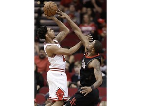 Chicago Bulls guard Cameron Payne, left, shoots as Houston Rockets forward Trevor Ariza defends during the first half of an NBA basketball game Tuesday, March 27, 2018, in Houston.