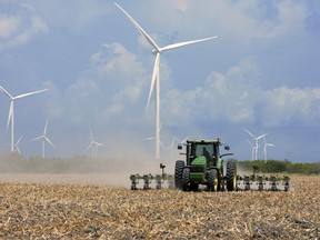FILE - In this Aug. 17, 2015, file photo, a farmer plows his recently harvested field under wind turbines in the agricultural area north of Rio Hondo, Texas, near the New Mexico border. New Mexico regulators on Wednesday, March 21, 2018, approved a $1.6 billion plan that calls for building two massive wind farms along the Texas-New Mexico border.