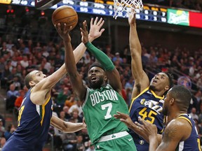 Boston Celtics guard Jaylen Brown (7) lays the ball up as Utah Jazz's Rudy Gobert, left, and Donovan Mitchell (45) defend in the second half of an NBA basketball game Wednesday, March 28, 2018, in Salt Lake City.
