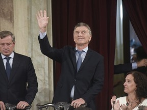 Argentina's President Mauricio Macri waves as he arrives to open the 2018 session of Congress and give the annual State of the Nation address, flanked by Emilio Monzo, president of the Chamber of Deputies, left, and Vice President Gabriela Michetti, in Buenos Aires, Argentina, Thursday, March 1, 2018.