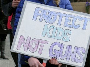 A student stands outside the Vermont statehouse with a sign that reads "Protect Kids Not Guns" on March 13, 2018, to support gun restrictions to prohibit gun violence.