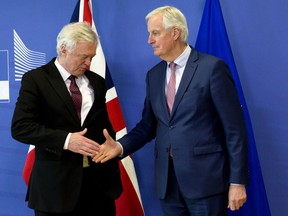 European Union chief Brexit negotiator Michel Barnier, right, reaches out to shake hands with British Secretary of State for Exiting the European Union David Davis prior to a meeting at EU headquarters in Brussels on Monday, March 19, 2018.