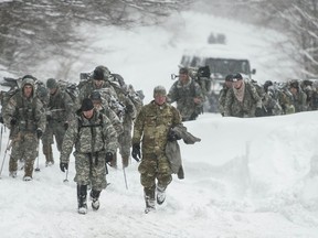 Vermont National Guard soldiers on a training exercise emerge from a closed section on Vermont 108 in Cambridge, Vt., just below Smuggers Notch on Wednesday night, March 14, 2018, after six soldiers were swept approximately 300 meters by an avalanche.