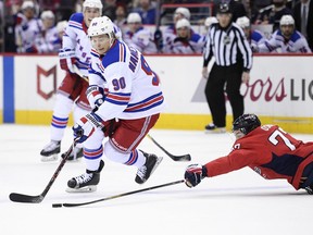 Washington Capitals right wing T.J. Oshie (77) lunges for the puck next to New York Rangers center Vladislav Namestnikov (90), of Russia, during the first period of an NHL hockey game Wednesday, March 28, 2018, in Washington.