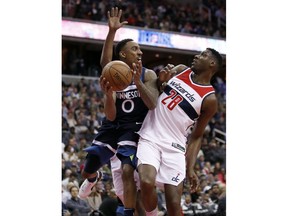 Minnesota Timberwolves guard Jeff Teague (0) looks to pass as he collides with Washington Wizards center Ian Mahinmi (28), from France, during the first half of an NBA basketball game, Tuesday, March 13, 2018, in Washington.