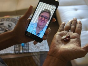 In this March 15, 2018 photo, public health nurse Peggy Cooley of the Tacoma-Pierce County Health Department, seen on the phone screen, uses Skype video to remotely monitor a patient taking antibiotics for tuberculosis at home in Lakewood, Wash. Researchers are testing how well smartphone apps that monitor pill-taking work when medication matters. Experts praise the efficiency, but some say the technology raises privacy and data security concerns.