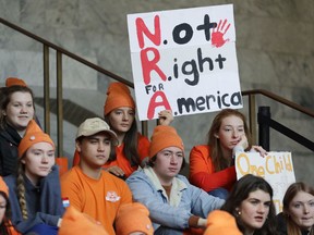 Lydia Ringer, 16, a junior at Roosevelt High School in Seattle, holds a sign that reads "NRA - Not Right for America," Tuesday, March 6, 2018, as she attends a rally against gun violence at the Capitol in Olympia, Wash. The rally was held on the same day Gov. Inslee was scheduled to sign a bill banning the sale and possession of gun bump stocks in the state of Washington.