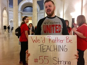 Jacob Staggers, a sixth-grade English teacher at South Middle School in Morgantown, W.Va., holds up a sign outside the state Senate chambers at the Capitol in Charleston, W.Va., on Thursday, March 1, 2018. Teachers returned to the Capitol to pressure lawmakers to push through teacher pay raises and monitor progress on a task force that will eventually address their insurance coverage.