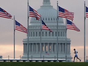 FILE - In this Sept. 27, 2017, file photo, a early morning runner crosses in front of the U.S. Capitol as he passes the flags circling the Washington Monument in Washington. With passage of an enormous budget bill, Congress has all but wrapped up its legislating for the year _ in March. Now lawmakers have to run on what they've got: a tax cut bill, big spending increases and no fixes to immigration.