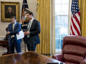 FILE - In this Jan. 31, 2018 file photo, White House aide John McEntee, right, and Treasury Secretary Steve Mnuchin's Chief of Staff Eli Miller, left, stand in the Oval Office as President Donald Trump speaks at a tax reform meeting with American workers at the White House in Washington. Trump's personal aide is leaving the White House and will rejoin his campaign.