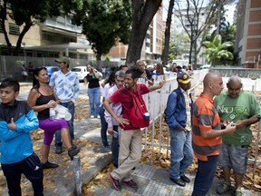 People stand in line to buy bread in Caracas, Venezuela, Friday, March 23, 2018. Venezuelan President Nicolas Maduro announced Thursday he's tackling the country's staggering inflation by lopping three zeros off the increasingly worthless bolivar currency. He said the new banknotes should begin circulating in early June.