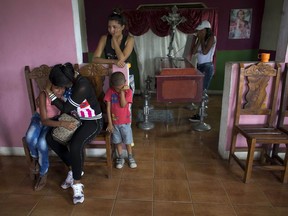 The coffin with the remains of Daniel Marquez sits in his living room as his daughter Feliana, 13, left, is consoled by her aunt Sorangel Gutierrez, in Valencia, Venezuela, Thursday, March 29, 2018. Marquez is one of 68 people killed in a fire that swept through a Venezuelan police station jail Wednesday.  "He didn't deserve to die like this," Gutierrez, Marquez's sister-in-law, said as relatives wept before his casket.