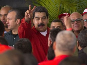 Venezuela's President Nicolas Maduro flashes a victory sign to supporters during a ceremony formalizing his candidacy as a candidate for the upcoming presidential election, at the CNE in Caracas, Venezuela, Tuesday, Feb. 27, 2018. Officials loyal to Maduro recently approved an early presidential election for April 22, drawing broad condemnation from the United States and several of Venezuela's Latin American neighbors who said the conditions for a fair election are lacking.